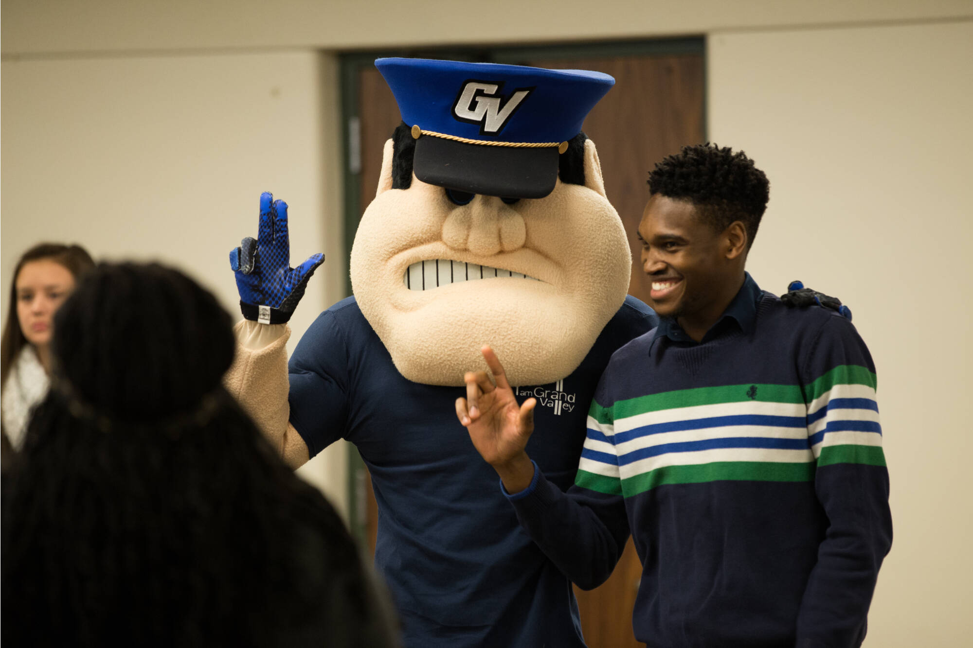 A student poses with GVSU mascot Louie the Laker, both showing 'Anchor Up,' at the I am GV Leadership Reception, Jan. 24, 2018